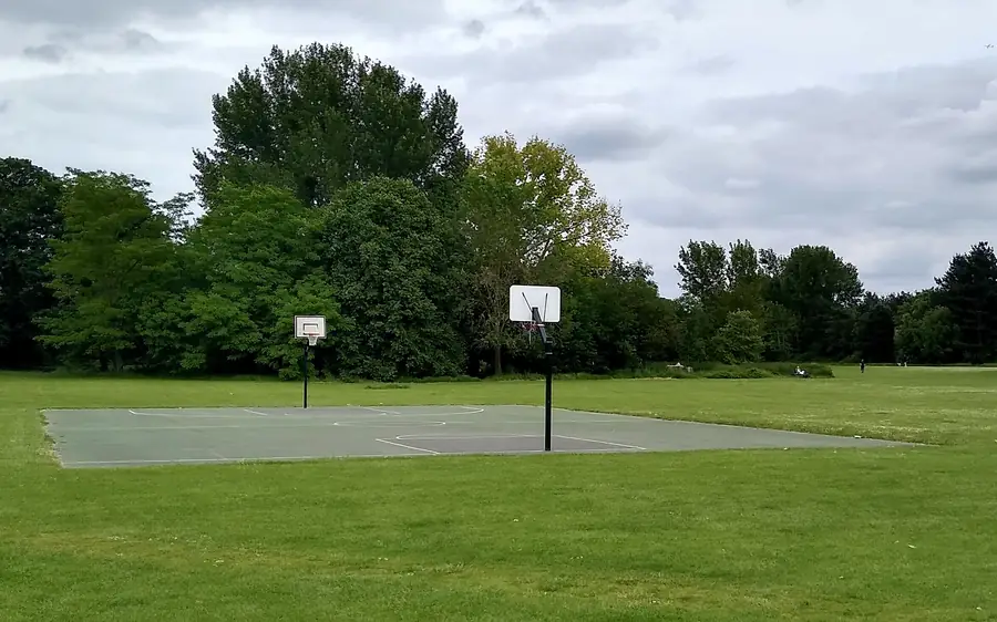 Campo de basquetebol ao ar livre num parque, com duas tabelas e o piso marcado